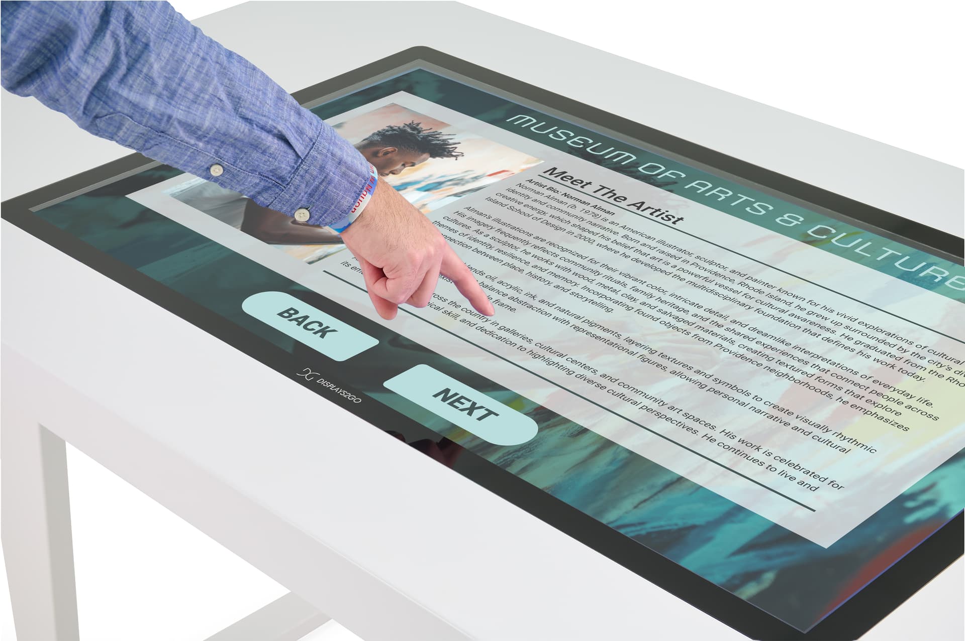 Interactive touch screen table with someone interacting with a graphic of an art museum bio for an artist