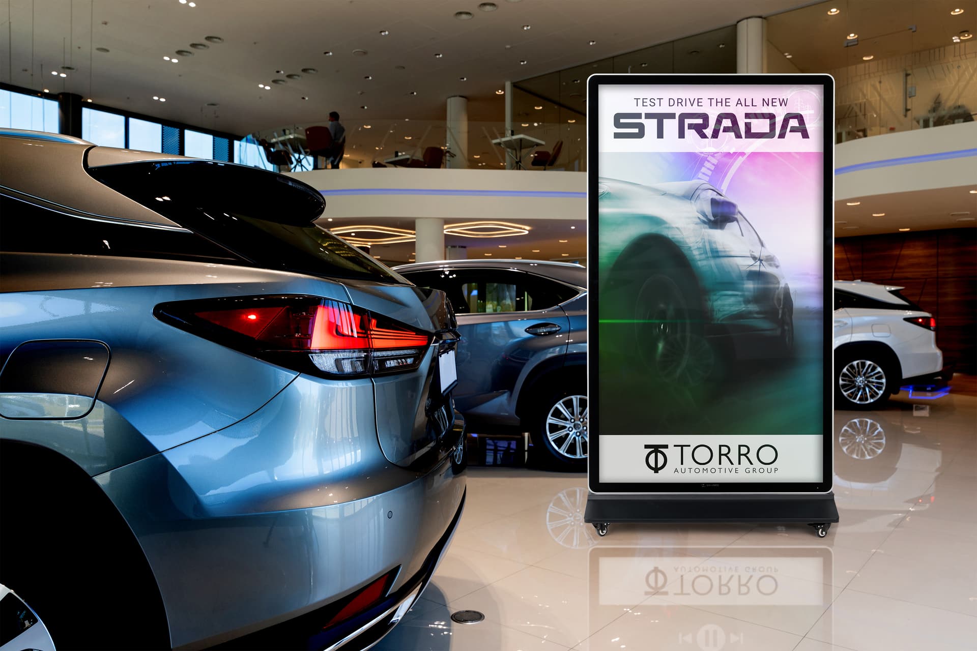 Digital display advertising floor stand being showcased inside a car dealership showroom featuring a video of a car advertisement 