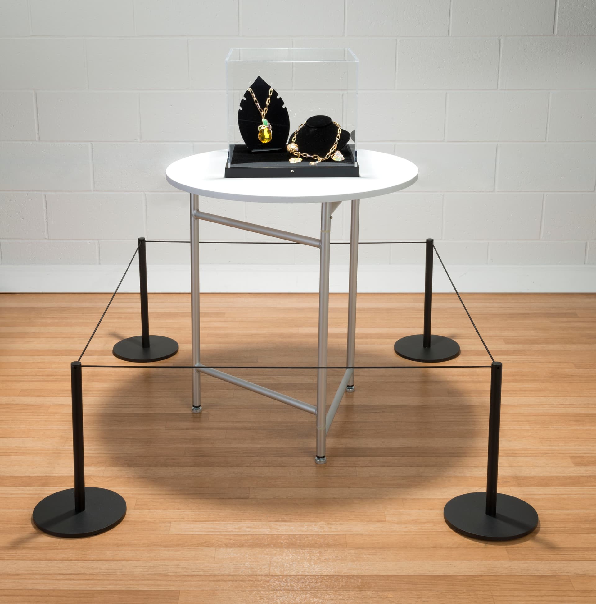 Black low profile exhibit stanchion connected to 3 other posts for a barricade around jewelry